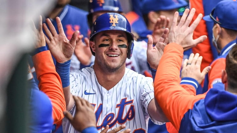 Mets' James McCann is congratulated in the dugout after scoring...