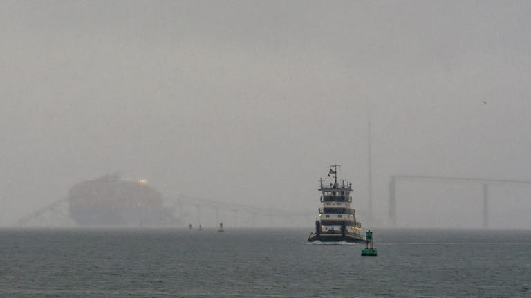A tugboat travels along the Patapsco River as the container...