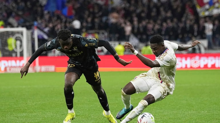 Lyon's Ernest Nuamah, right, challenges for the ball with Reims'...