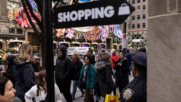Shoppers and sightseers walk along 5th Avenue, Dec. 11, 2023,...