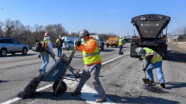 Workers patch potholes along the westbound Long Island Expressway, between Exits 57 and...
