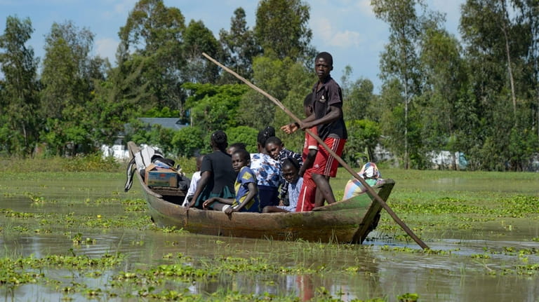 A family uses a canoe after fleeing floodwaters that wreaked...