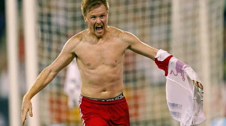 Red Bulls' Dax McCarty pulls off his jersey after scoring...