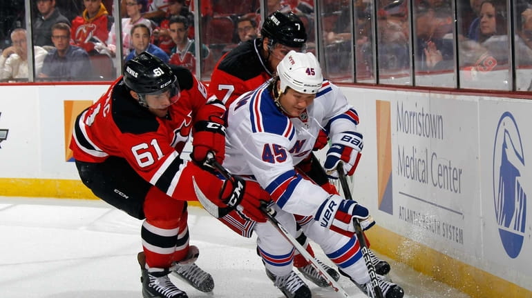 Arron Asham of the Rangers (no. 45) moves the puck...