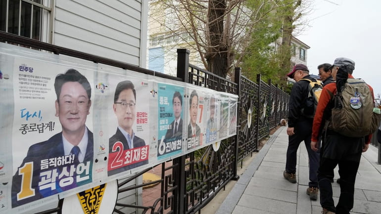 People pass by posters of candidates running for the upcoming...