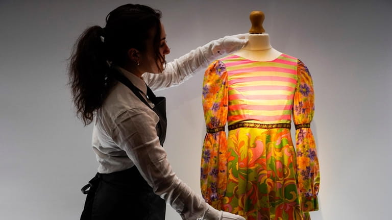 A member of staff poses next to a dress from...