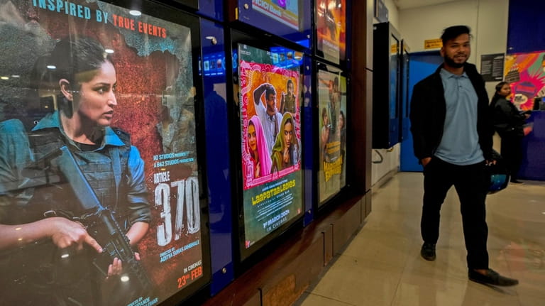 A man stands next to a poster of the movie...