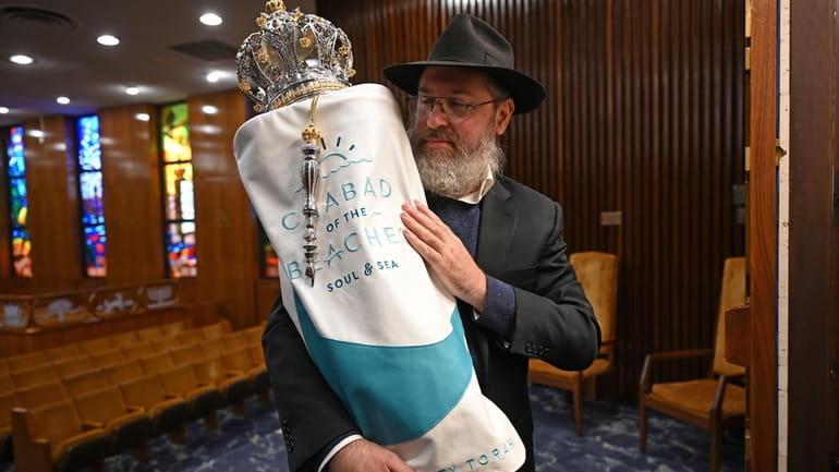 Rabbi Eli Goodman of Chabad of the Beaches holds one of...