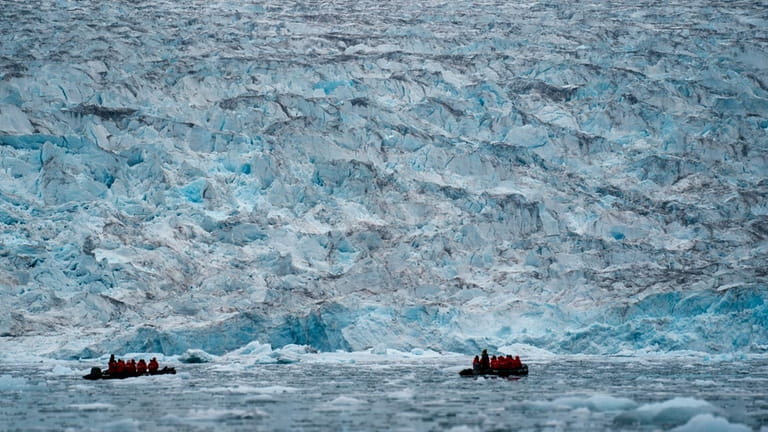 Two groups from the Poseidon Expeditions look at a glacier...