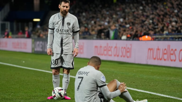 PSG's Lionel Messi stands next to injured PSG's Kylian Mbappe...
