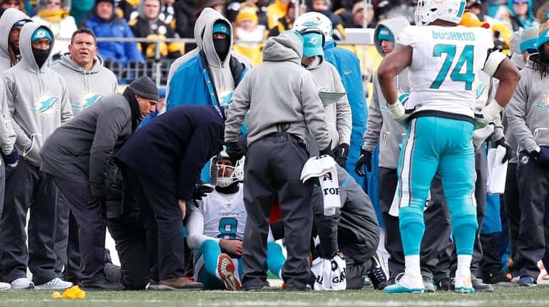 Trainers look at Matt Moore of the Miami Dolphins after...