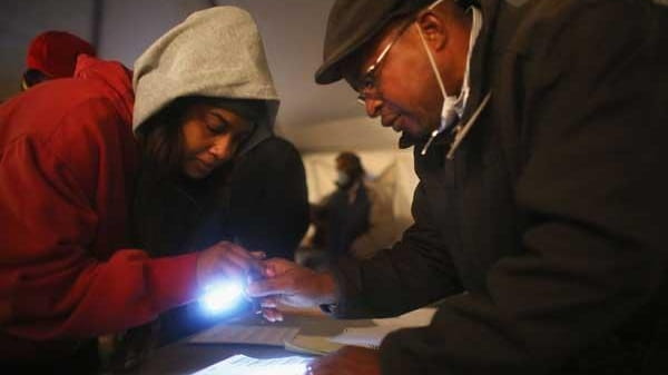 Sheresa Walker, left, uses a flashlight before voting in a...