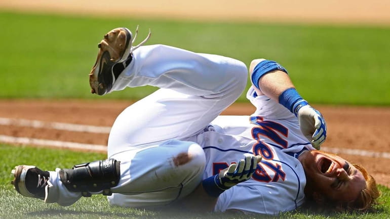 Justin Turner reacts in pain after a fall diving back...