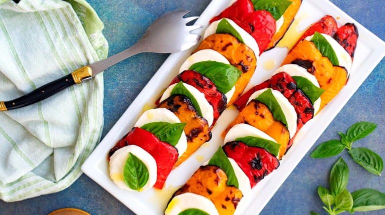 Grilled peppers layered between sliced fresh mozzarella and bay leaves.