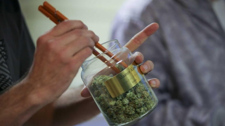 An employee pulls marijuana out of a large canister for...
