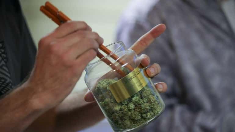 An employee pulls marijuana out of a large canister for...