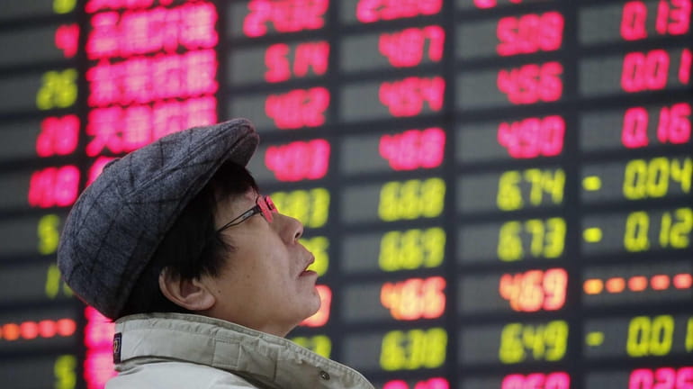 An investor looks at the stock price monitor at a...