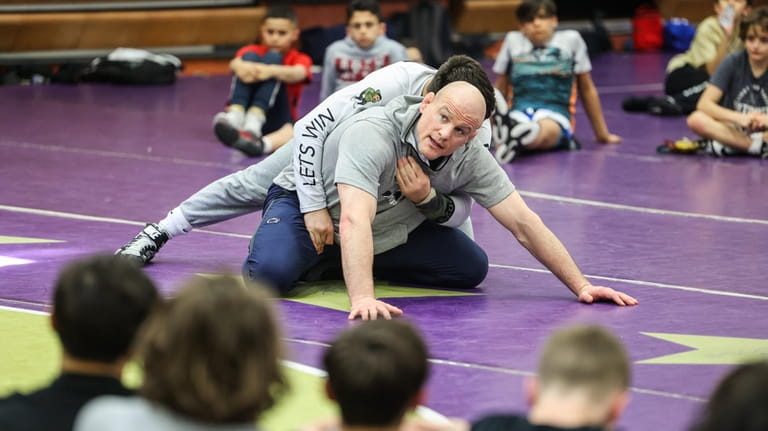 Penn State University wrestling coach Cael Sanderson works with P.J....