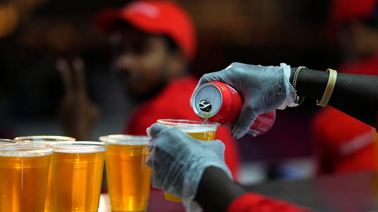 FILE - Staff member pours a beer at a fan...