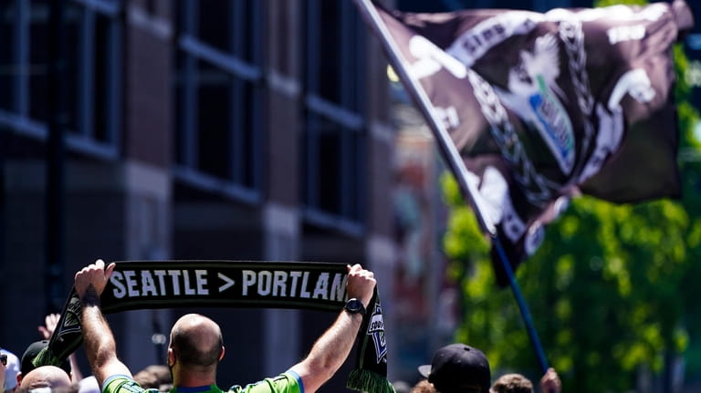 A fan holds a scarf reading "Seattle > Portland" during...