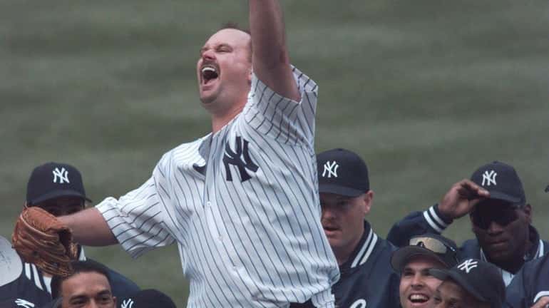 David Wells waves to the crowd as he is carried...