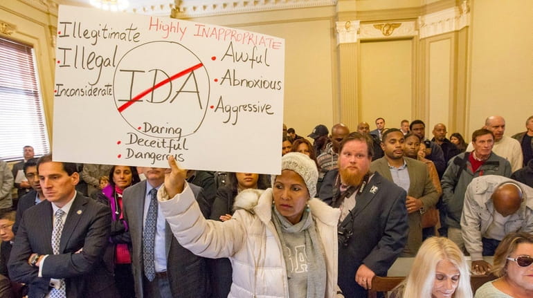 Jinette Frederique holds a sign at a Hempstead Town IDA...