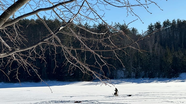 An ice fisherman stands on the frozen Molly's Falls Pond...
