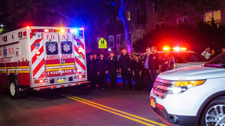 FDNY EMTs and firefighters stand at attention as the body...