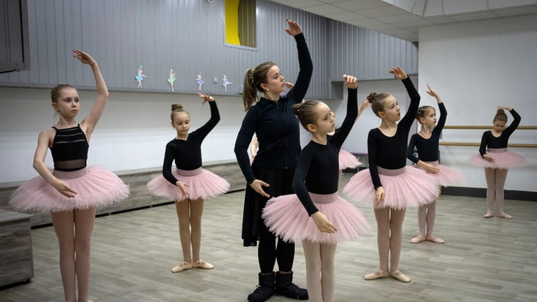 A ballet coach teaches girls in a ballet studio in...