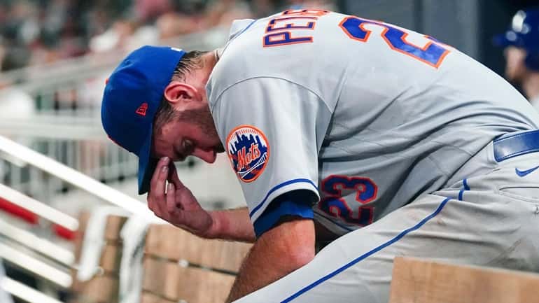 Mets starting pitcher David Peterson stands in the dugout after being...