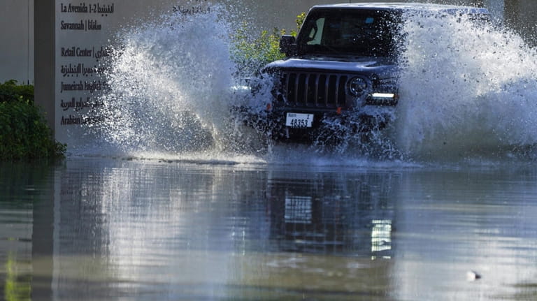An SUV drives through floodwater covering a road in Dubai,...