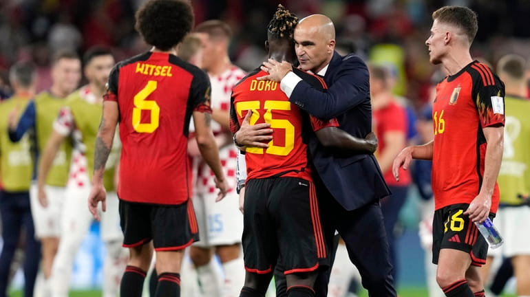 Belgium's head coach Roberto Martinez embraces Belgium's Jeremy Doku after...