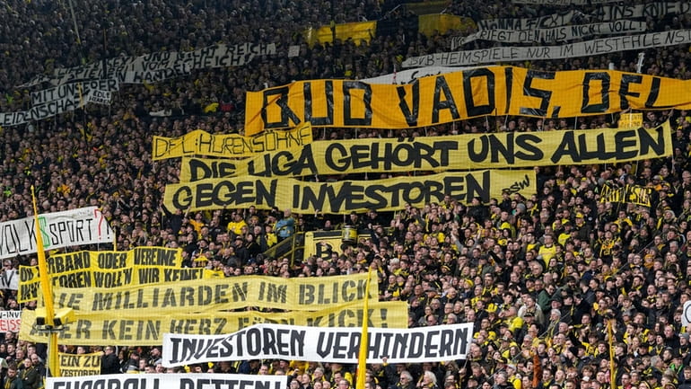 Fans hold up banners protesting against investors in German soccer...
