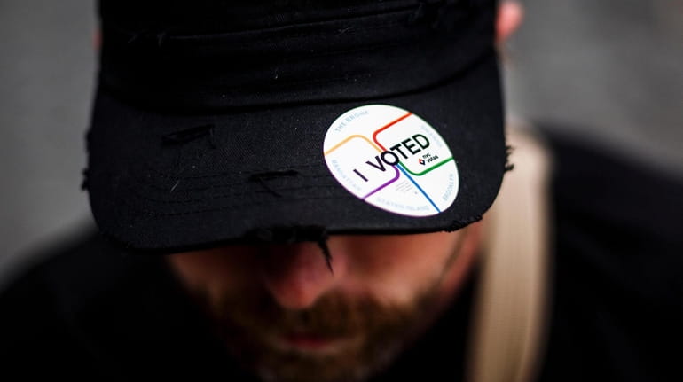 A man wears a "I Voted" sticker on his hat during...