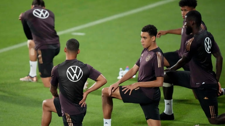 Germany's Jamal Musiala stretches besides team mates during a training...