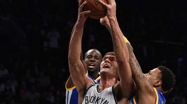 Nets' Brook Lopez is defended under the basket by Warriors'...