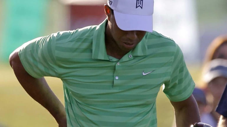 Tiger Woods rubs his back after his tee shot on...