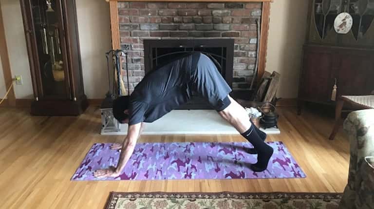John Lalena strikes a downward-dog yoga pose at home in...