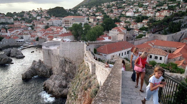 Tourists walk on the city wall that rings the historic...