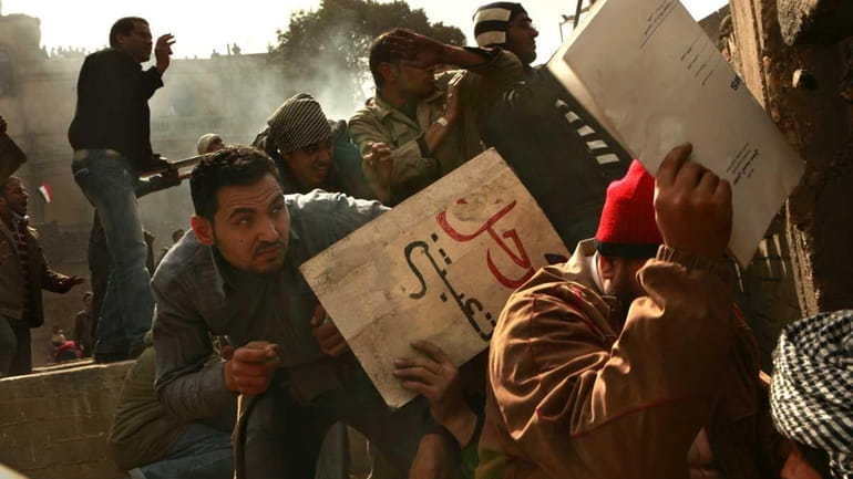 Anti-Hosni Mubarak protesters, hiding behind makeshift shields, throw rocks Thursday...
