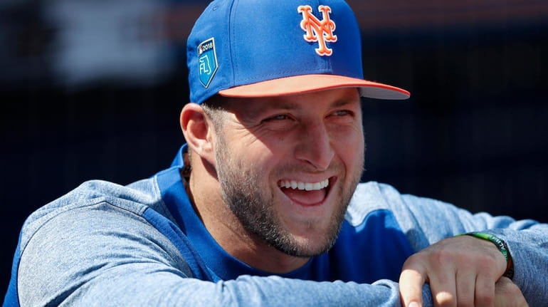 The Mets' Tim Tebow laughs with teammates in the dugout...