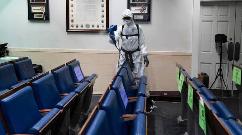 A member of the White House staff sprays disinfectant Monday...