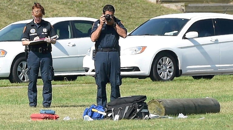 Suffolk County police on the athletic field look at a...