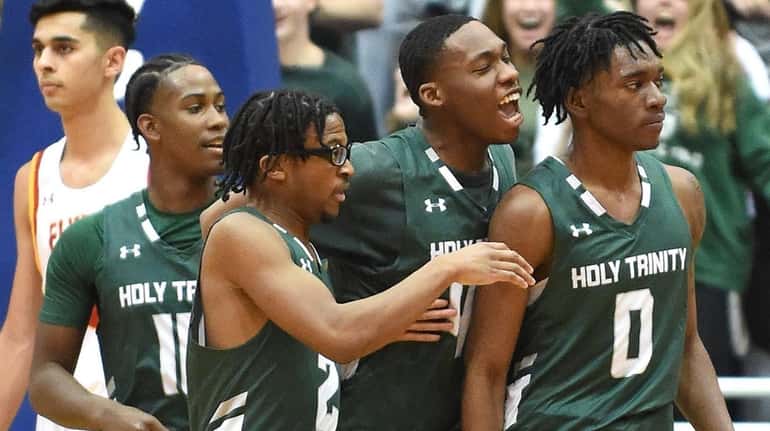 Manu Alford of Holy Trinity, right, gets mobbed by teammates...