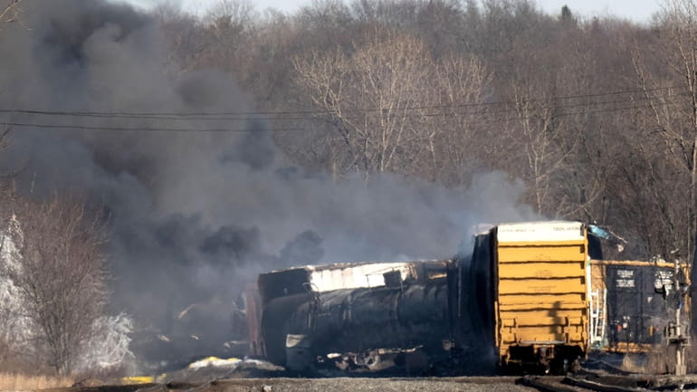 Smoke rises from the derailed cargo train in East Palestine, Ohio, sending dozens...