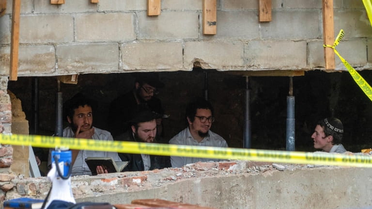 Hasidic Jewish students sit behind a breach in the wall...