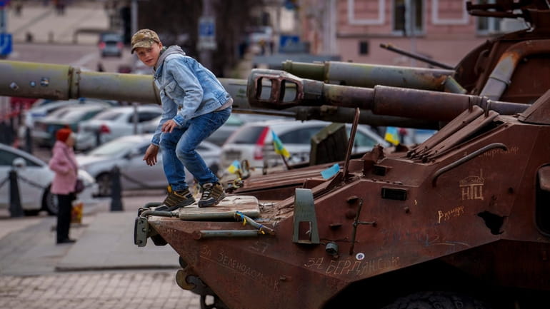 A child climbs on a rusty armored personnel carrier, part...