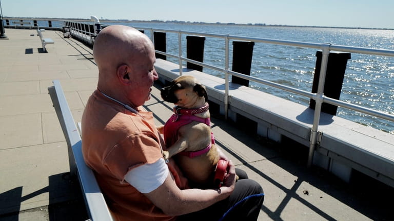 Howie Prusack enjoys the sunshine at Woodmere Dock with his dog,...