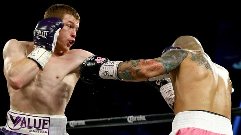Canelo Alvarez throws a left at Miguel Cotto during their...