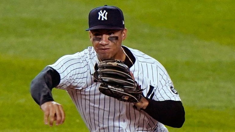 Yankees shortstop Gleyber Torres makes an errant throw while trying...